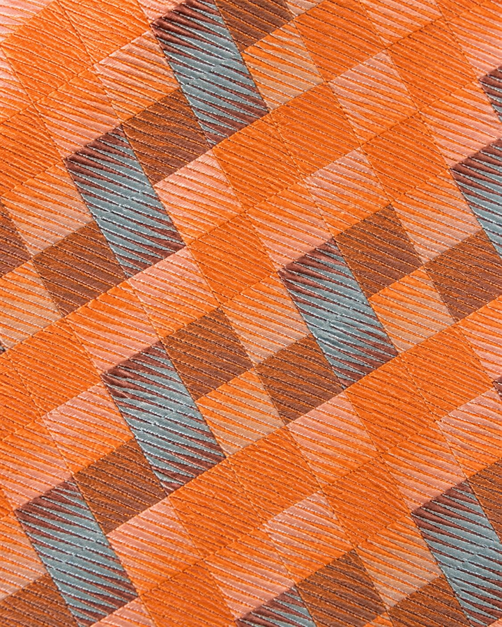 Närbild av flerfärgat argylemönster med rutstruktur på Averna, bröstnäsduk i orange, beige, brunt och grått