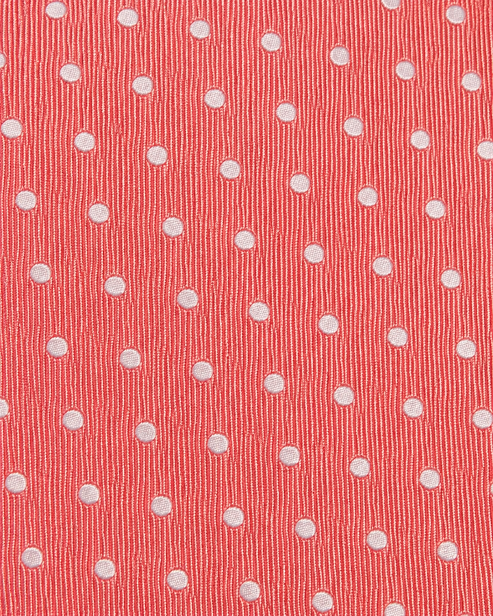 Närbild av regelbundet placerade små vita prickar på rosa botten på CARL, bred slips i rosa och vitt