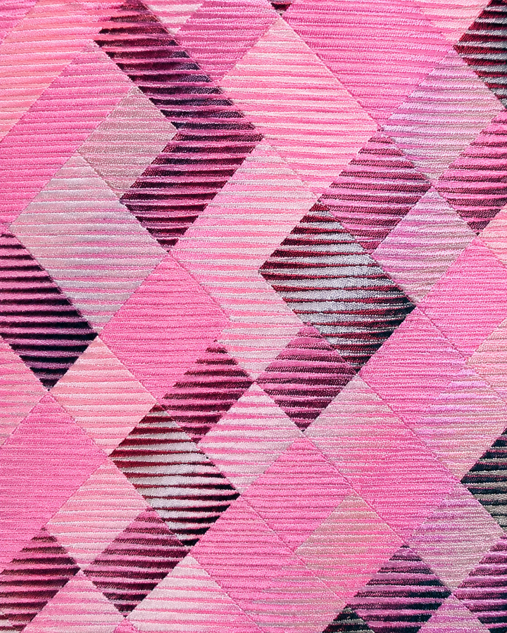 Närbild av grupperade mörkt kolbruna fyrkantsformer och fyrkantsband på rosa botten på CERES, bred slips i rosa och mörkt kolbrunt