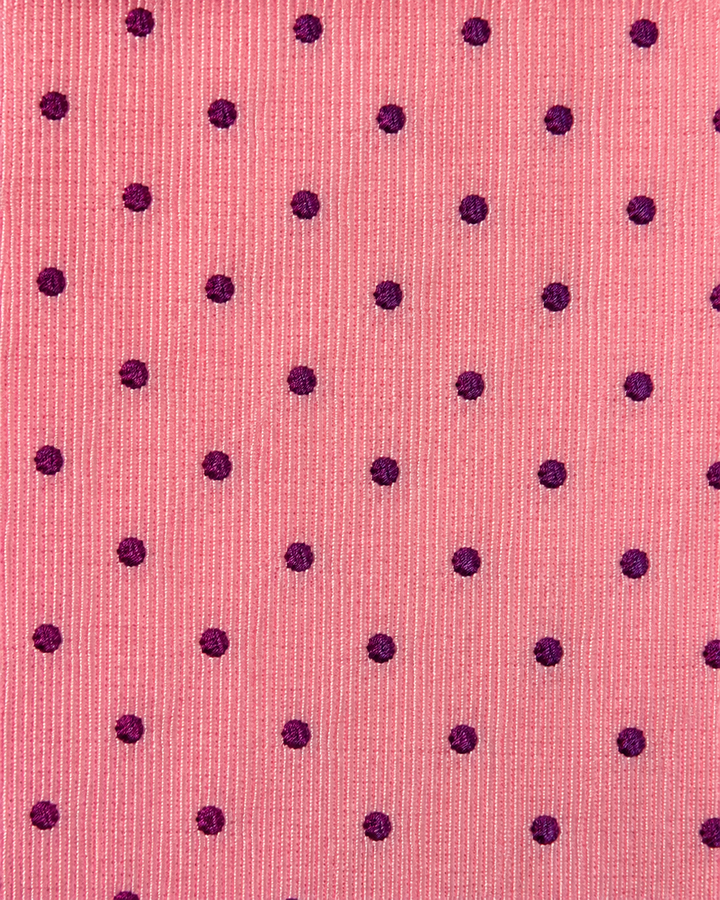 Närbild av regelbundet upprepade mörkt purpursvarta prickar på rosa botten på CONCORDIA, bred slips i rosa och mörkt purpursvart