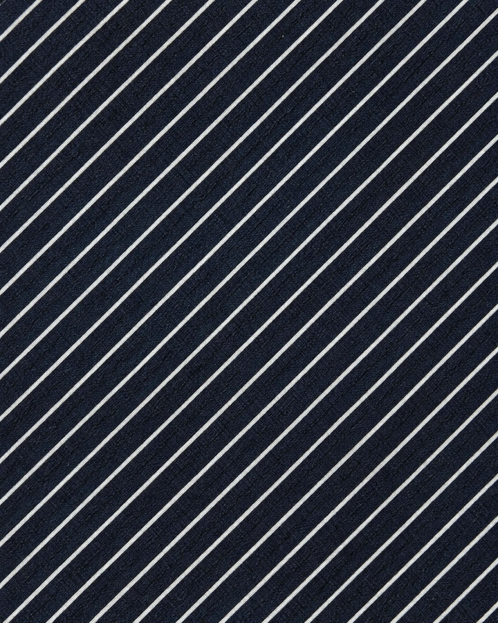 Närbild av täta fina vita diagonala pinstripes på mörkblå botten på CUT, bred slips i mörkblått och vitt