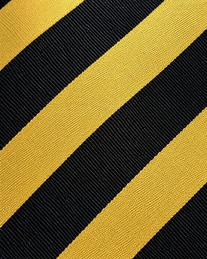 Närbild av breda diagonala band i svart och guld på DANIEL, bred slips i svart och guld