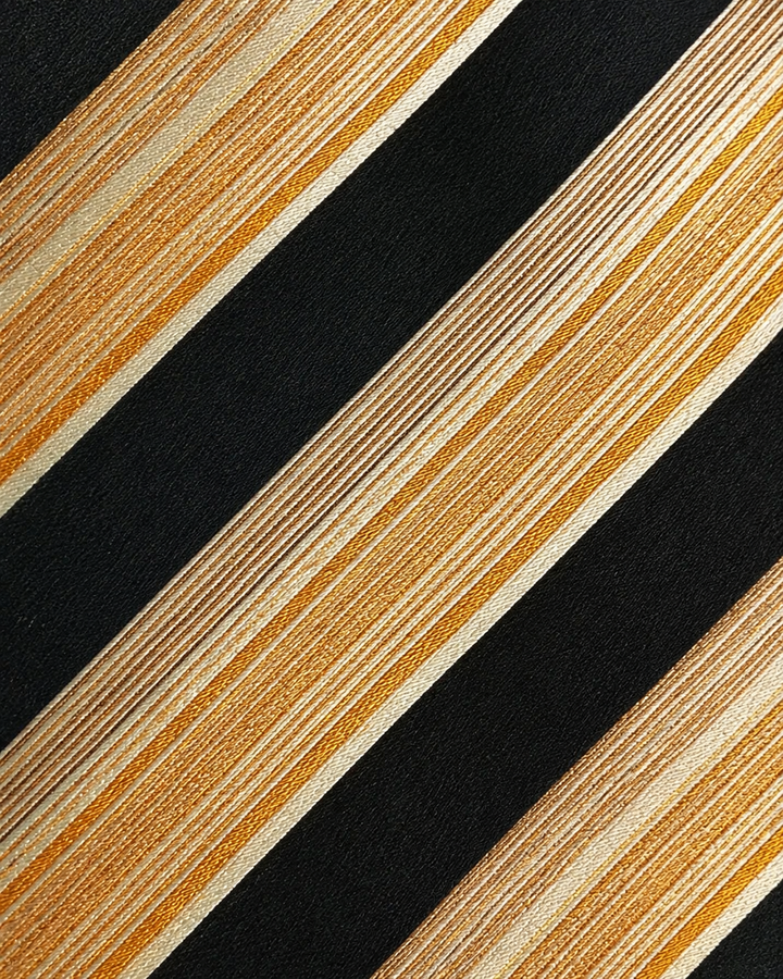 Närbild av randigt mönster på ELIS, bred slips i svart, gult, guld och orange