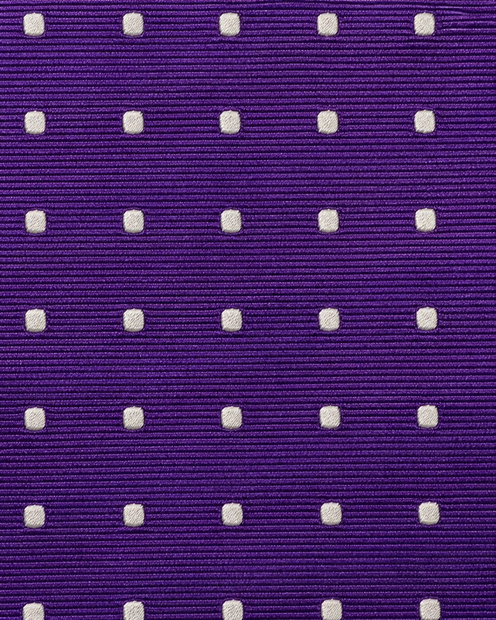 Närbild av tydliga vita prickar över en diskret vävd randstruktur på lila botten på JEHU SMAL, smal slips i lila och vitt