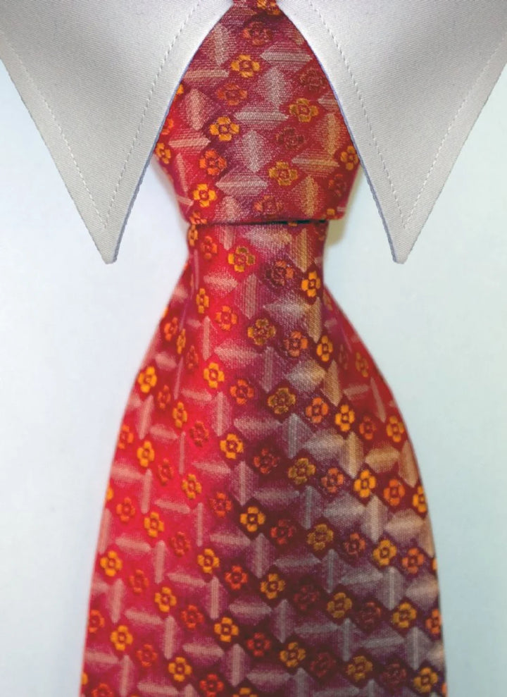 JUSTITIA, bred slips i orange, rött och guld med ett tätt upprepat orange- och guldfärgat blomdiamantmotiv på mörk orange-röd botten – originalbild