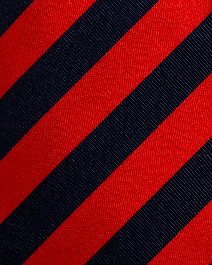 Närbild av randigt mönster på LASSE, bred slips i svart, rött och blått