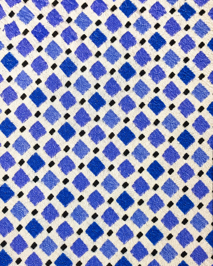 Närbild av ett tätt upprepat mönster av blå diamantformade rutor med små mörka accentdiamanter på vit botten på MAIA SMAL, smal slips i vitt, blått och mörkblått