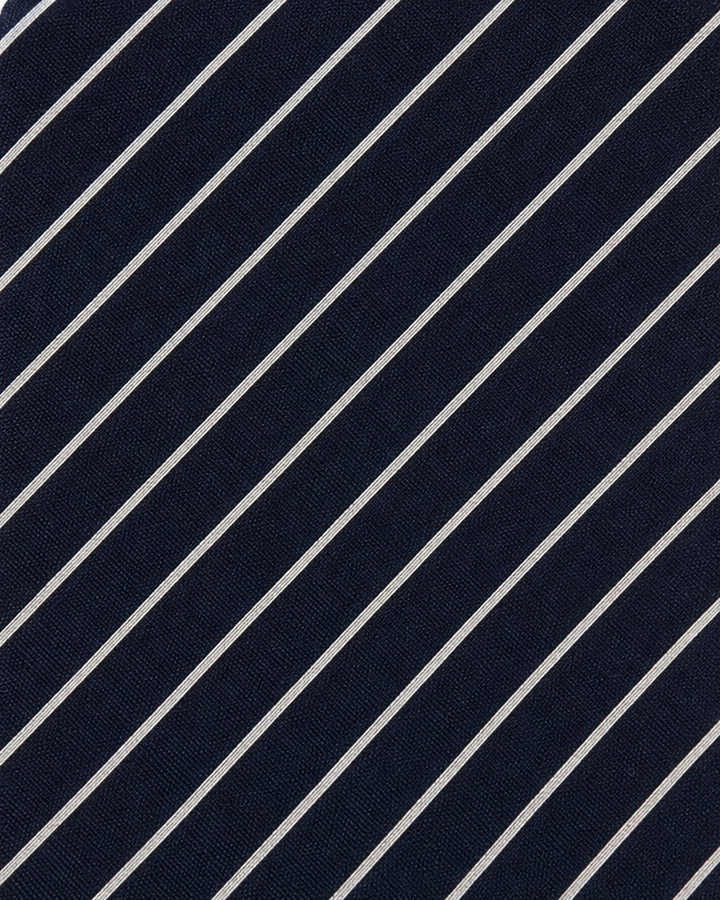 Närbild av smala vita och silverfärgade diagonala ränder på mörkblå botten på MARINA, bred slips i mörkblått, vitt och silver