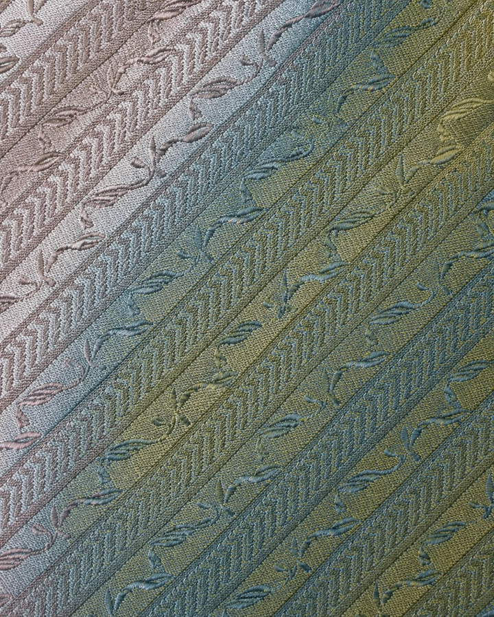 Närbild av upprepade bladmotiv ordnade i diagonala silverband på MEFITIS, bred slips i silver