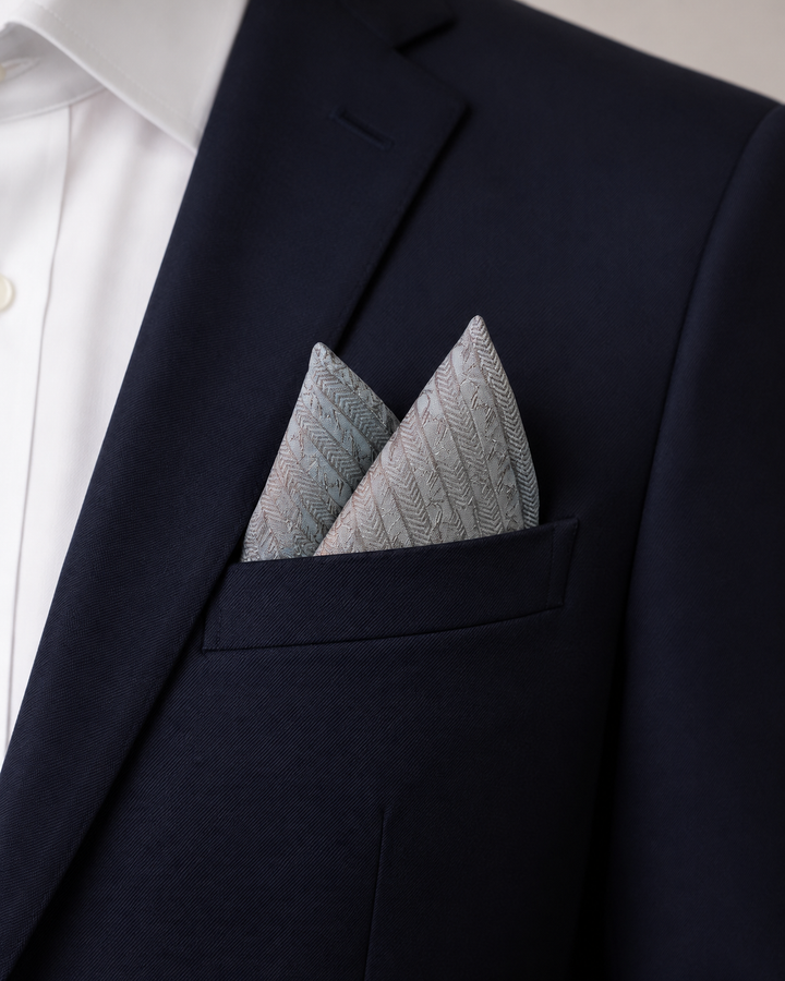 MEFITIS, bröstnäsduk i silver med upprepade bladmotiv ordnade i diagonala silverband, formellt stylad