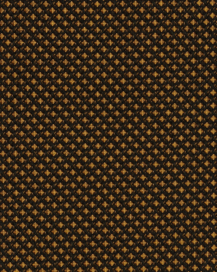 Närbild av ett tätt mönster av små orange prickar på svart botten på MESH, bred slips i svart och orange