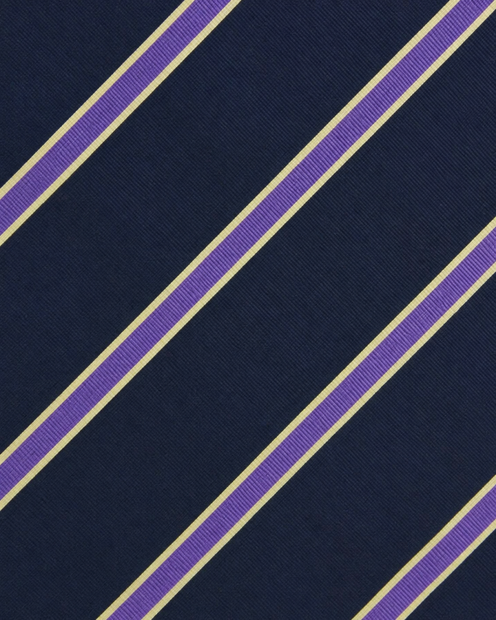 Närbild av parade lila och ljusa silvervita diagonala accentlinjer på mörkblå botten på NEMO, bred slips i mörkblått, lila och silvervitt
