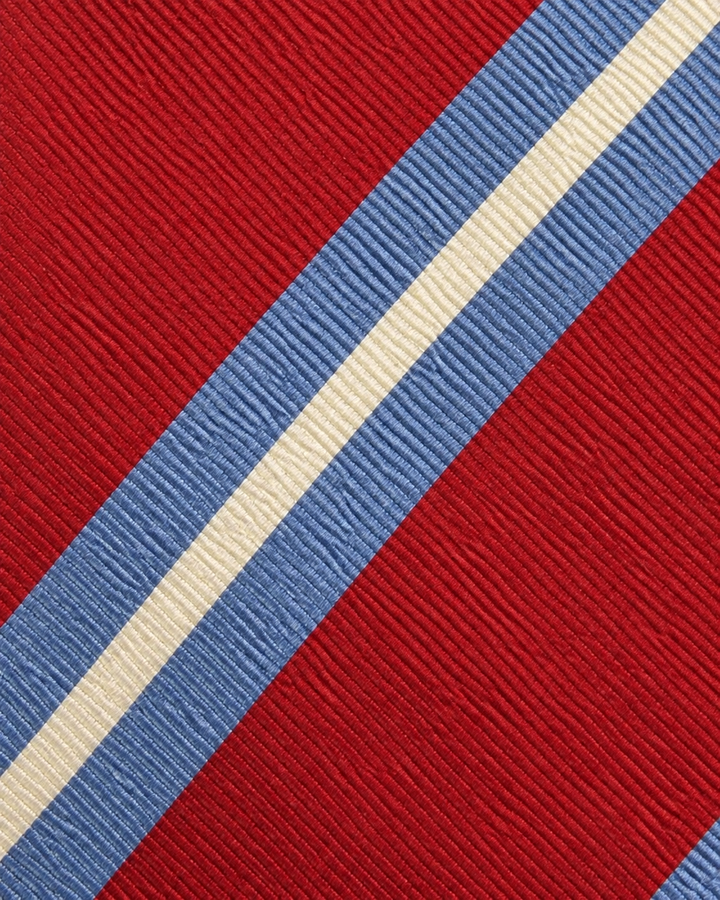 Närbild av breda röda och blå diagonala band åtskilda av framträdande vita accentband på OLOV, bred slips i rött, blått och vitt