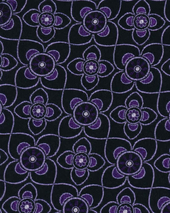 Närbild av stora lila blommotiv på svart botten på OMIKRON, slips i svart och lila