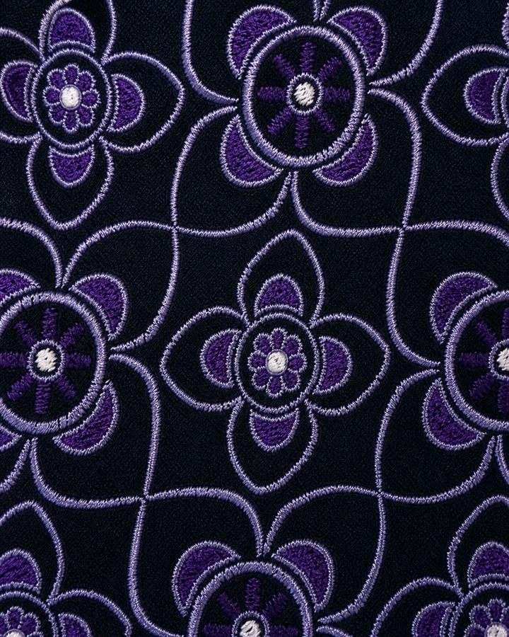 Närbild av blommigt motiv på OMIKRON SMAL, smal slips i lila och svart