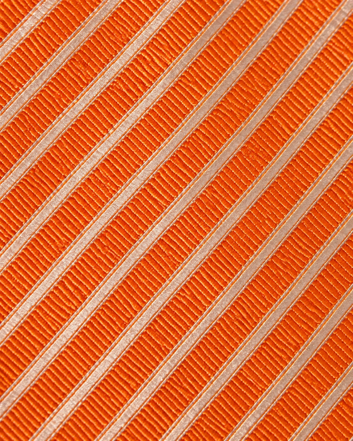 Närbild av randigt mönster på SIXTEN, bred slips i vitt och orange