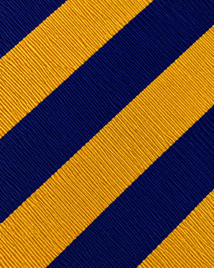 Närbild av breda diagonala band i guld och blått på SVEDALA, bred slips i guld och blått