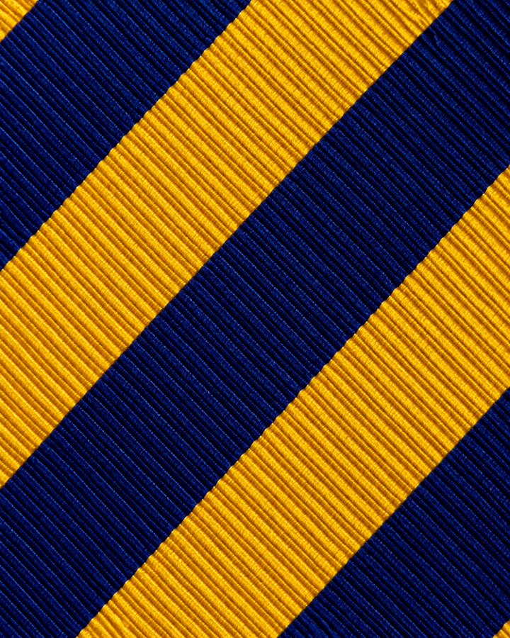 Närbild av breda diagonala band i guld och blått på SVEDALA SMAL, smal slips i guld och blått
