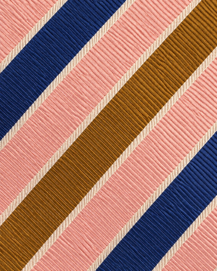 Närbild av breda diagonala blå, rosa och varmt brunguldfärgade band med smala vita mellanband på TAFFY, bred slips i blått, rosa, varmt brunguld och vitt