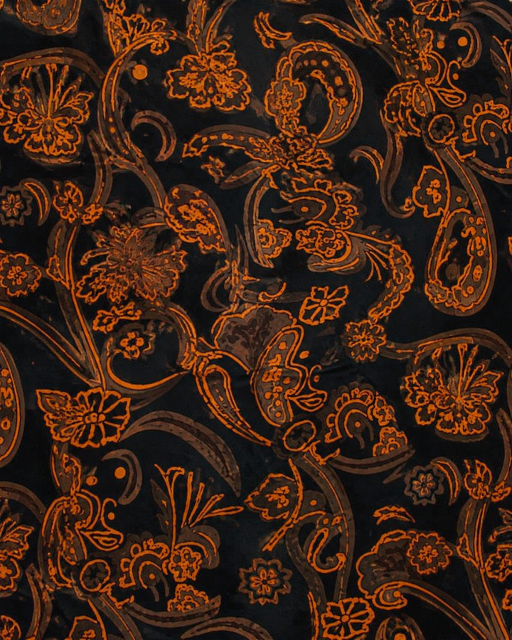 Närbild av stora orange paisleymotiv på svart botten på TAU, slips i svart och orange