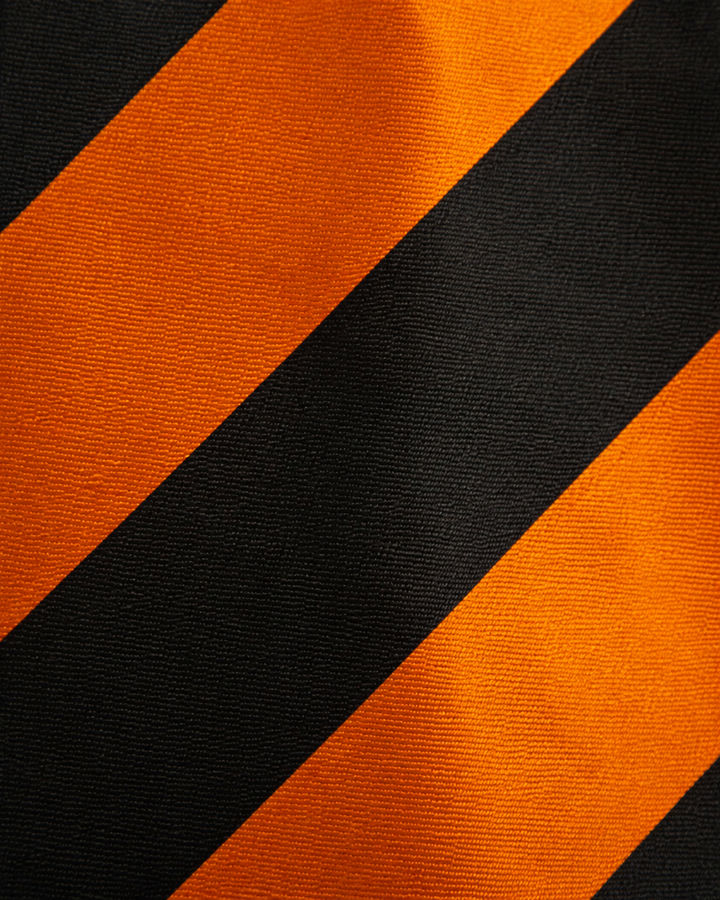 Närbild av randigt mönster på TOBIAS, bred slips i svart och orange