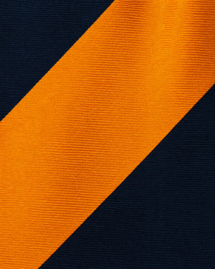 Närbild av randigt mönster på TOBIAS SMAL, smal slips i svart och orange