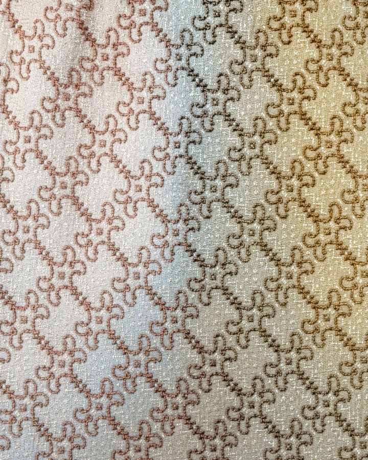 Närbild av ett tätt sammanlänkat konturmönster i brunguld på blekt silverfärgad botten på XI SMAL, smal slips i blekt silver och brunguld